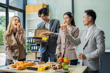 Asian business team are excited business success with inspiration from their excellent financial results, celebration successful deal with champagne and pizza in the workplace.