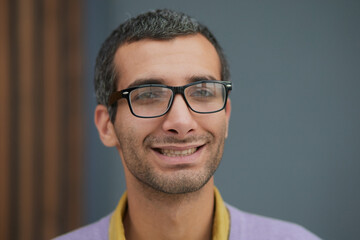 Close-up of a handsome adult man, wearing a lilac t-shirt, smiling happily