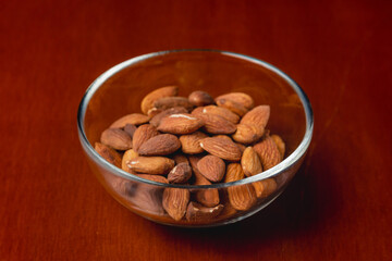 Almond nut in glass plate on wooden background