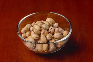 Pistachio nuts in glass plate on wooden background