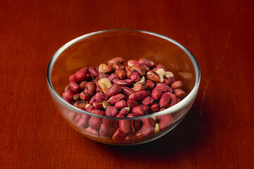 Roasted peanuts in glass plate on wooden background