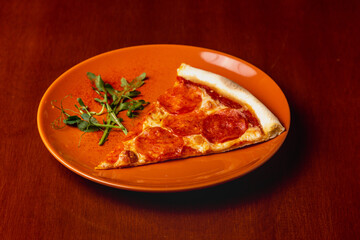 Slice of pepperoni pizza on plate on wooden background