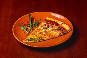 Slice of cheese pizza on plate on wooden background