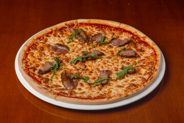 Italian pizza with roast beef and cheese on a plate on a wooden background
