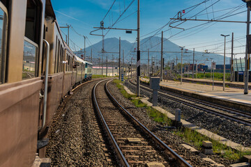 Museum train in italy driving from Napoli main station towards Pietrarsa train museum. Sunny day, visible tracks leading towards magnificent mount Vesuvius, volcano.