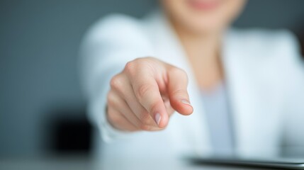 Female Business Professional in White Blazer Pointing at Camera, Engaging Viewers with Confident and Friendly Gesture in Modern Office Setting