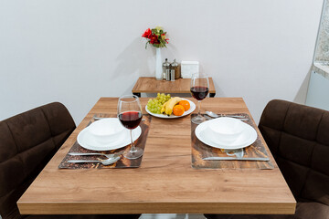 There is a beautifully crafted wooden table that has been set with plates and elegant wine glasses placed neatly upon it, creating an inviting dining atmosphere for gatherings
