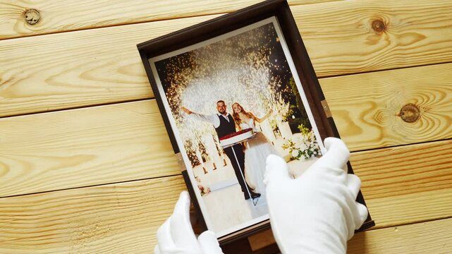 hands in white gloves and Beautiful printed wedding photos. take out of the box