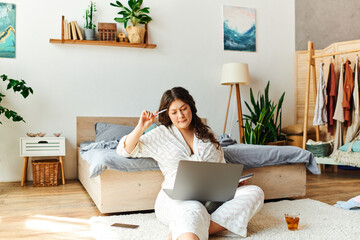 A young plus size woman enjoys her laptop while relaxing in a stylish, inviting bedroom.