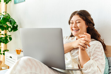 A cheerful plus size woman smiles brightly while engaged in an online conversation at home.