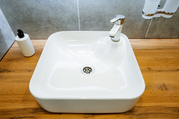 A white sink is sitting on a wooden counter in a bathroom