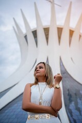 Woman in white dress poses in front of the iconic Cathedral, showcasing modern architecture.