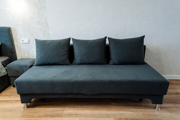 In a cozy living room, there is a stylish black couch adorned with three decorative pillows that enhance its appearance and comfort, creating an inviting atmosphere for relaxation