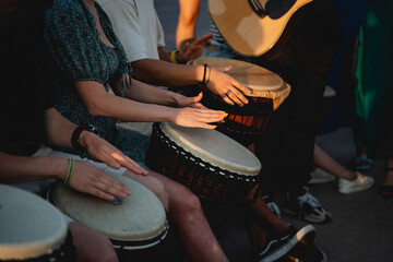 A lively group of people are enthusiastically playing drums while a talented man skillfully plays a...