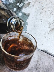 Pouring cola drink with ice cubes