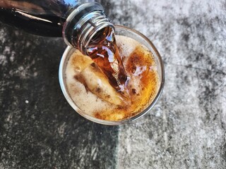 Pouring cola drink with ice cubes