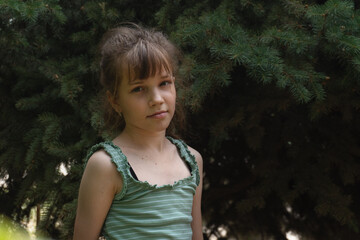 Portrait of a teenage girl 10 or 11 years old against a background of spruce