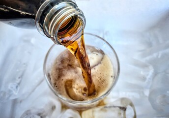 Pouring cola drink with ice cubes