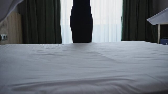 Unrecognizable woman making bed in hotel room. Maid cleaning room. Hotel room service.