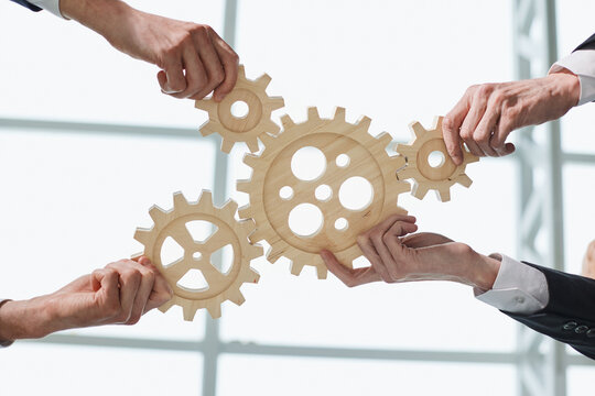 Hands of people office workers business partners making common picture of wooden gears on table, selective focus