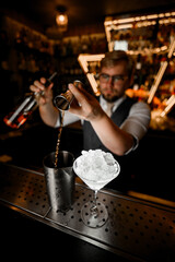 Top view of bar counter with martini glass with crushed ice and metal mixing glass