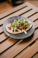 A dish in a black plate on a wooden table