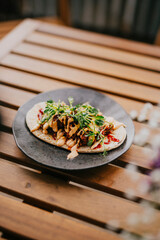 A dish in a black plate on a wooden table