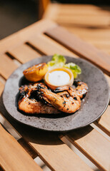 A beautiful dish made with grilled prawns served in a black plate with a white sauce