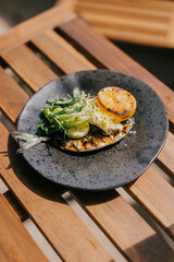 A dish in a black plate on a wooden table