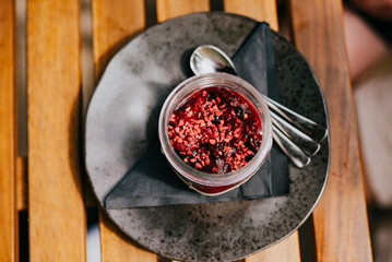 top view of a dessert cup in a black plate with a steel spoon 