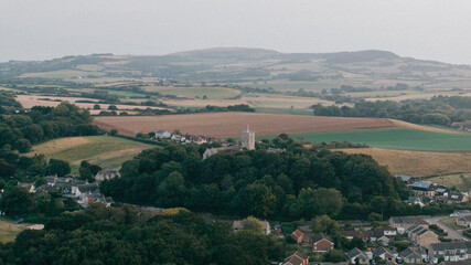Aerial view of a town in a forest and a huge open field of farm