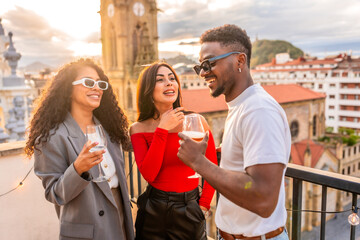 Multi-ethnic friends chatting and drinking wine in a rooftop