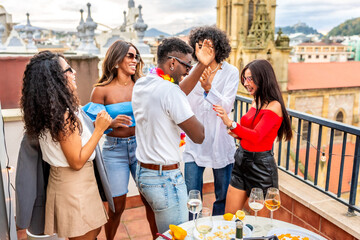 Multiracial friends dancing happily during tropical party in a rooftop