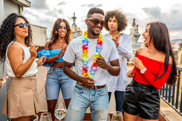 Man with Hawaiian necklace dancing with friends in outdoor party