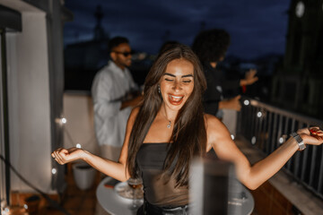 Happy woman dancing during night party on a city rooftop