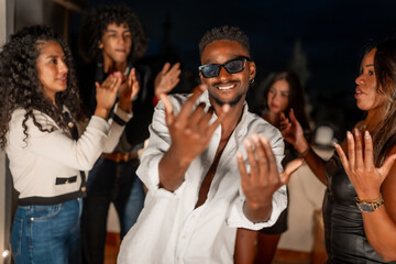 Cool man gesturing while dancing surrounded by friends at night