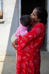 Indian woman in red sari kisses baby