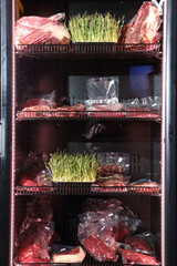 Beef steaks are kept in a special refrigerator before being cooked. Steaks in airtight packaging in the refrigerator. Maturing steaks before cooking. Beef steaks in refrigerator.