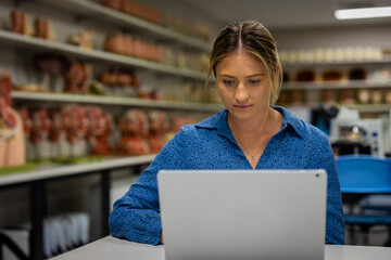 Young woman anatomy science biology student and researcher in a health and medical laboratory using laptop computer to read and analyze study information.