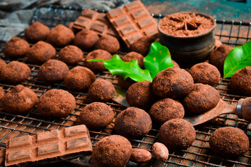 Sweet chocolate truffles with cocoa powder. On a dark chocolate background. Cocoa beans.