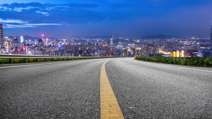 Obraz premium Scenic Cityscape at Night with a Curved Road Leading into the Skyline