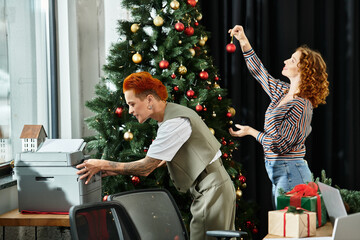 A cheerful moment of young colleagues enhancing their workspace with festive decorations.