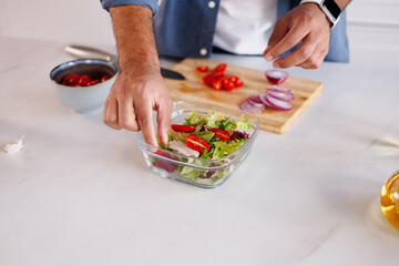 Close up of african american man cooking fresh salad near cutting board in kitchen
