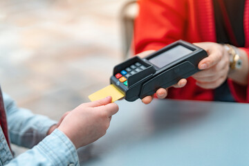 Person using a card to make contactless payment at a modern café during the day