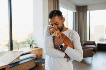 Young african american man holding chihuahua dog at home