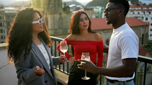 Multi-ethnic friends having an interesting conversation in a rooftop with city views during sunset