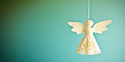 A delicate angel ornament with lace wings and dress, hanging against a soft gradient background.