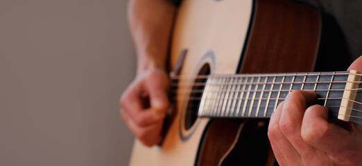 Fototapeta premium Hands playing acoustic guitar. Guitar music as form of self-expression creating personal and unique sound. solo guitarist plays at home capturing essence of relaxation and creativity. Banner