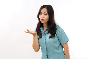 Indignant displeased Asian woman concentrated away has sad expression raises hand with clueless look wears casual shirt earrings poses against white background copy space for text or promotion