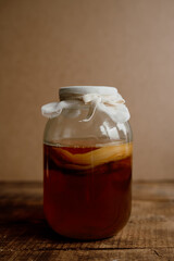 Glass jar with kombucha drink on a wooden background. Homemade healthy drink with probiotic